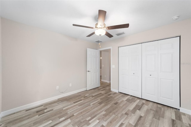unfurnished bedroom featuring light wood-style flooring, a closet, baseboards, and visible vents