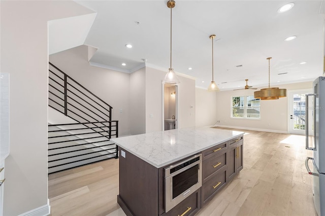 129 SE Watula Ave, Ocala, FL 34471 - kitchen with light wood-style flooring, open floor plan, ornamental molding, and stainless steel appliances