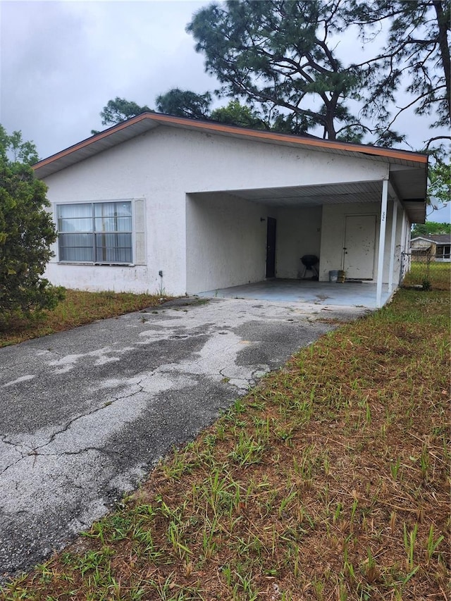 view of side of property with driveway, a carport, and stucco siding
