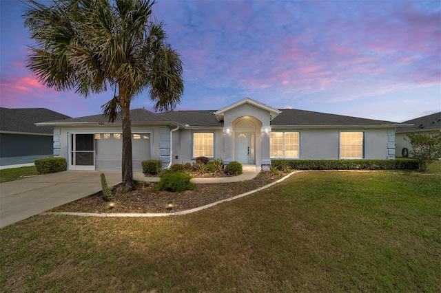 single story home featuring driveway, stucco siding, a yard, and an attached garage