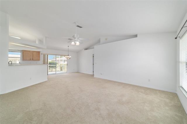 unfurnished living room featuring vaulted ceiling, ceiling fan with notable chandelier, baseboards, visible vents, and light carpet
