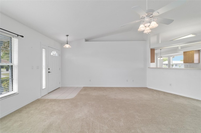spare room featuring vaulted ceiling, light carpet, light tile patterned floors, baseboards, and ceiling fan