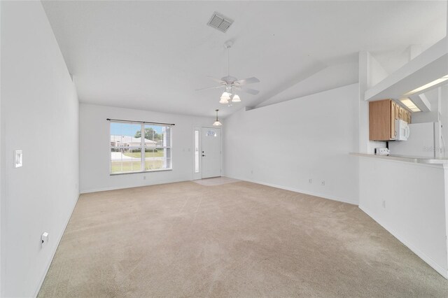 spare room with lofted ceiling, baseboards, light colored carpet, visible vents, and ceiling fan