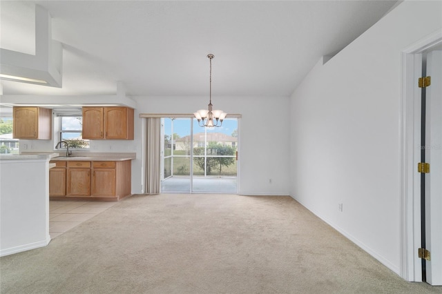 kitchen featuring light countertops, a sink, light colored carpet, decorative light fixtures, and an inviting chandelier