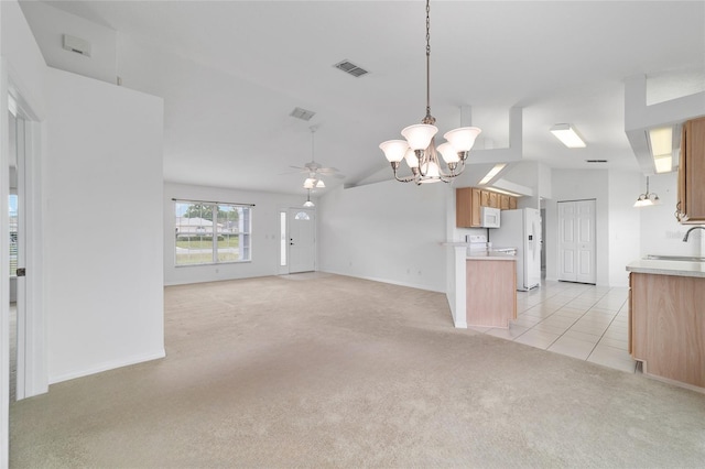unfurnished living room featuring vaulted ceiling, light colored carpet, ceiling fan with notable chandelier, a sink, and visible vents