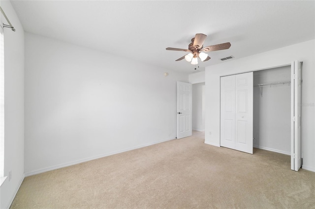 unfurnished bedroom featuring a closet, baseboards, light colored carpet, visible vents, and ceiling fan