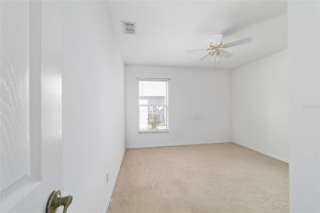 unfurnished room featuring baseboards, a textured ceiling, carpet floors, visible vents, and a ceiling fan
