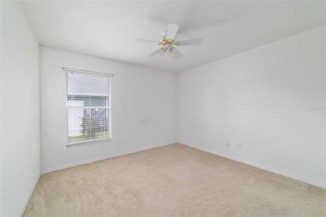 empty room with light colored carpet, ceiling fan, and baseboards