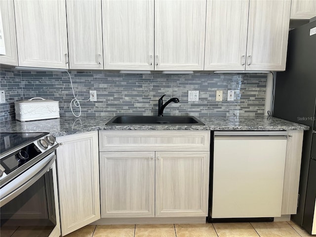 kitchen with electric stove, light stone countertops, light tile patterned floors, dishwasher, and a sink