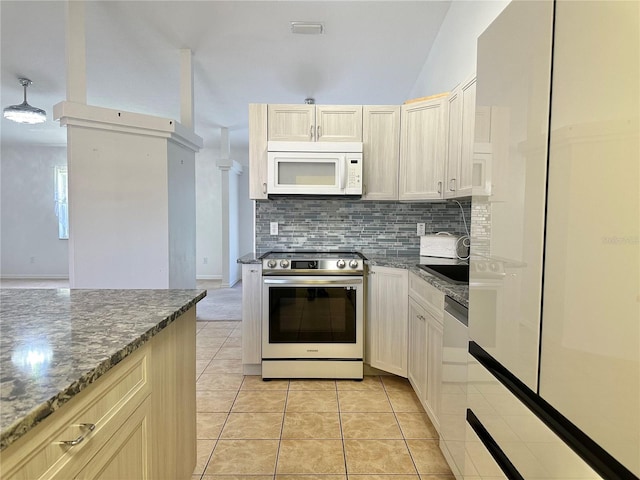 kitchen with light tile patterned floors, stainless steel appliances, backsplash, and dark stone counters