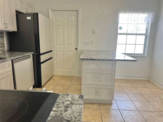 kitchen featuring light tile patterned floors, light stone counters, dishwashing machine, and cooktop