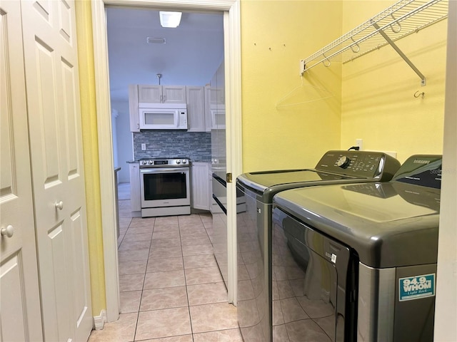 clothes washing area featuring light tile patterned floors, washer and clothes dryer, and laundry area