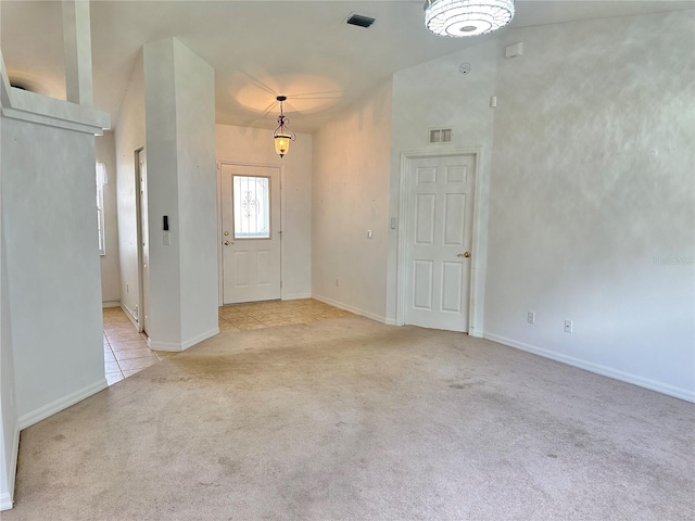 foyer featuring light tile patterned floors, visible vents, baseboards, and light carpet