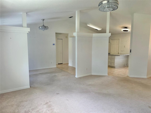 spare room featuring lofted ceiling, light carpet, and baseboards