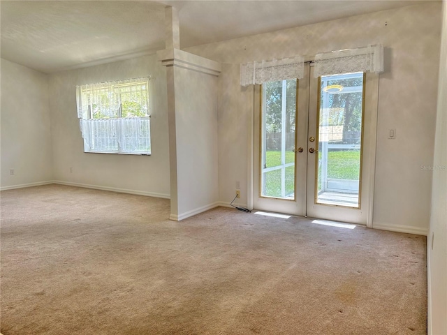 carpeted empty room featuring baseboards and french doors