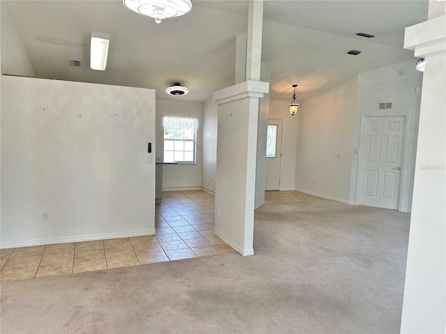 carpeted empty room featuring tile patterned floors, baseboards, visible vents, and lofted ceiling
