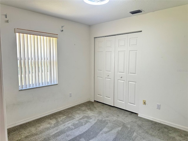 unfurnished bedroom featuring a closet, visible vents, carpet, and baseboards