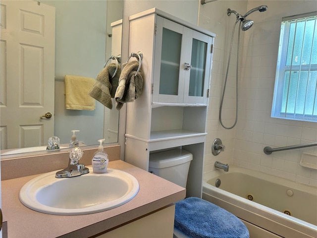 bathroom featuring toilet, a combined bath / shower with jetted tub, and vanity