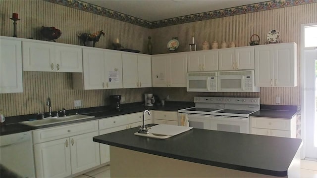 kitchen with wallpapered walls, a sink, white appliances, and dark countertops