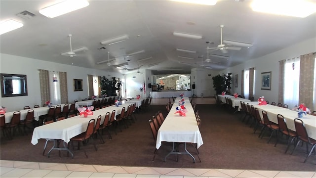 tiled dining room featuring visible vents, a ceiling fan, and vaulted ceiling