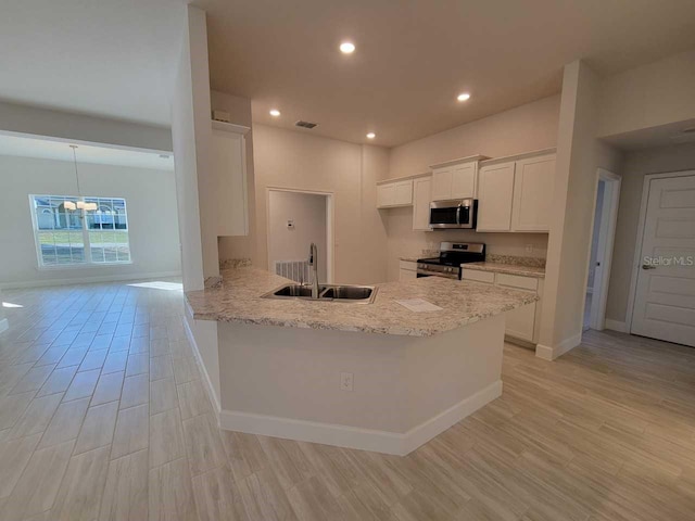 kitchen featuring white cabinetry, a sink, light wood finished floors, and appliances with stainless steel finishes