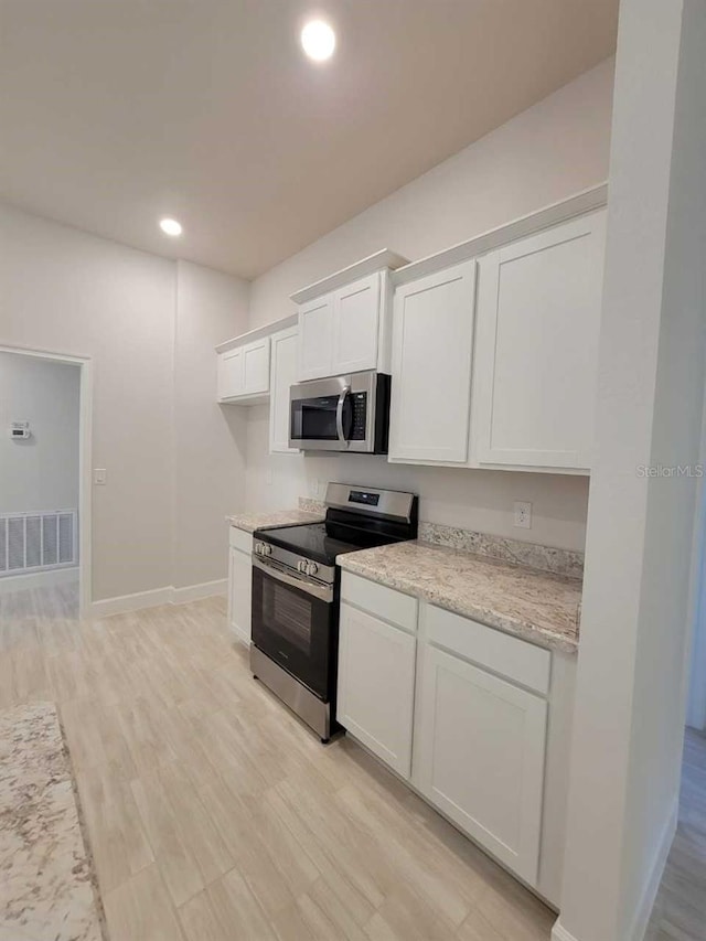 kitchen featuring white cabinetry, visible vents, light wood-type flooring, and stainless steel appliances