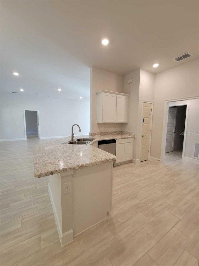 kitchen featuring light stone counters, a sink, dishwasher, visible vents, and white cabinets