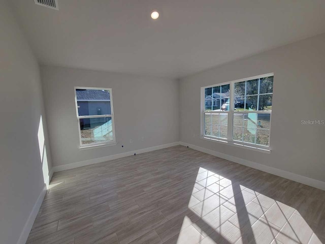 unfurnished room with visible vents, baseboards, and wood finished floors