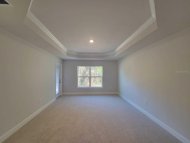 unfurnished room featuring visible vents, crown molding, baseboards, a tray ceiling, and light colored carpet