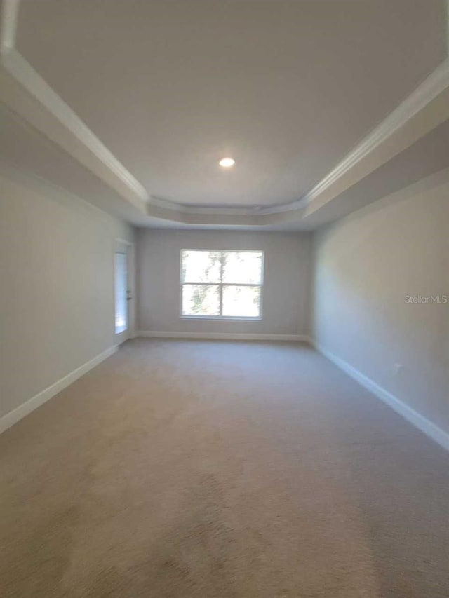 unfurnished room featuring baseboards, a tray ceiling, crown molding, and light carpet