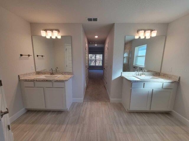 bathroom featuring visible vents, a sink, and two vanities