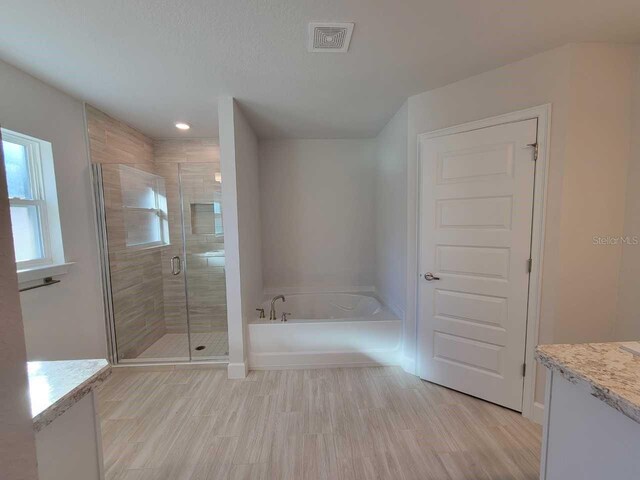 full bathroom with vanity, a shower stall, wood finished floors, a bath, and visible vents