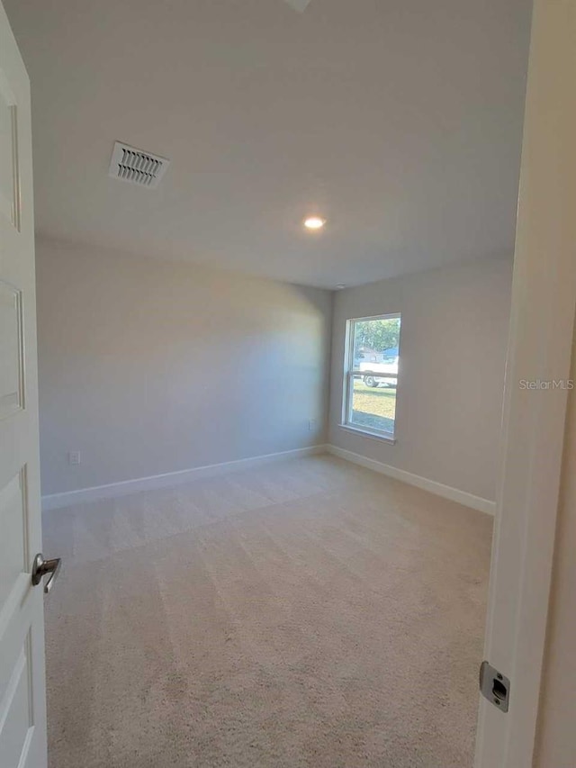 empty room with baseboards, visible vents, recessed lighting, and light colored carpet