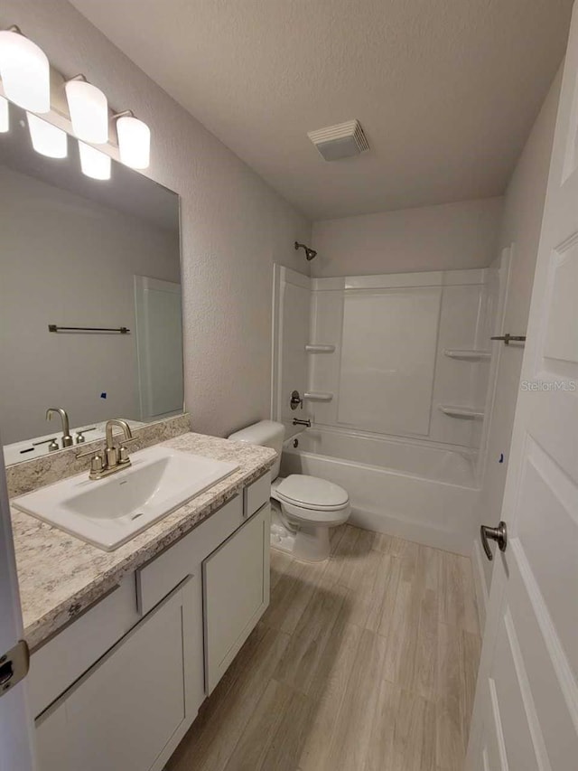 bathroom with toilet, wood finished floors, a textured ceiling, visible vents, and shower / bath combination