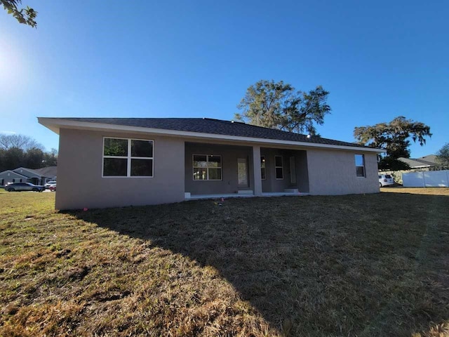 rear view of house with a lawn and stucco siding