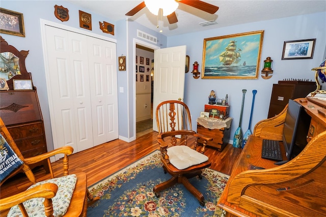 living area with visible vents, baseboards, a ceiling fan, and wood finished floors