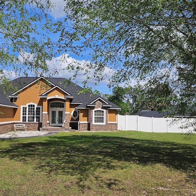 view of front of home with stucco siding, fence, french doors, and a front yard