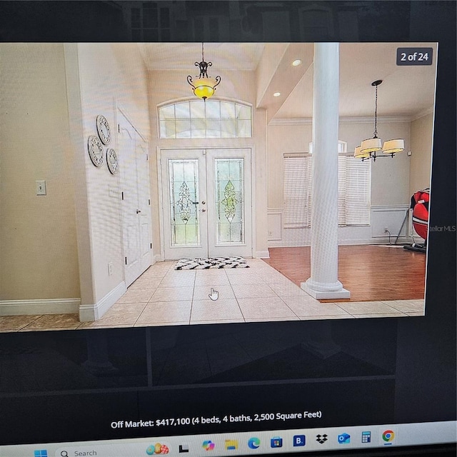 entryway with crown molding, decorative columns, an inviting chandelier, french doors, and baseboards