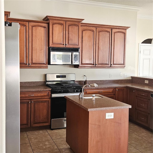 kitchen featuring light tile patterned flooring, ornamental molding, stainless steel appliances, a center island with sink, and a sink