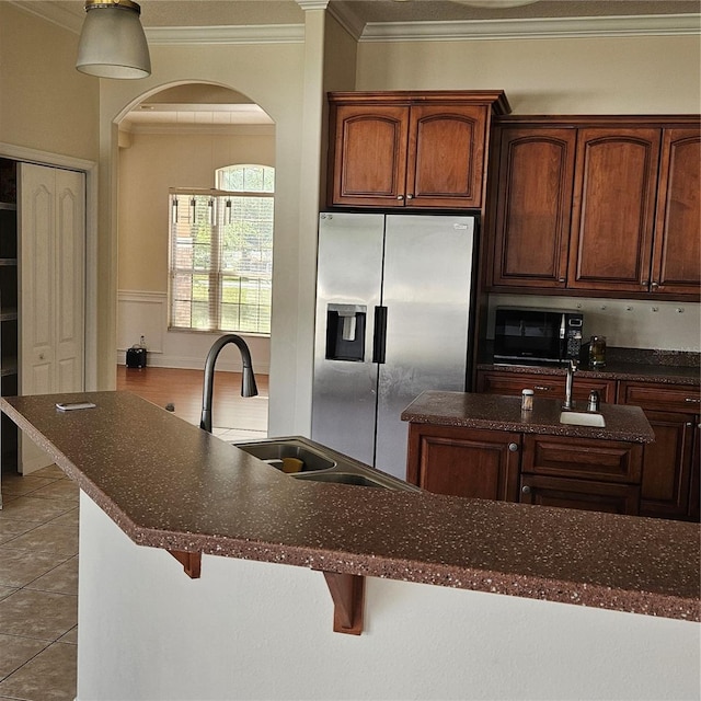 kitchen with ornamental molding, stainless steel fridge with ice dispenser, a sink, arched walkways, and black microwave