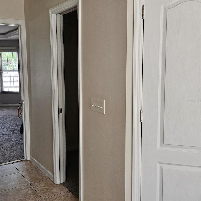 corridor featuring baseboards and light tile patterned floors