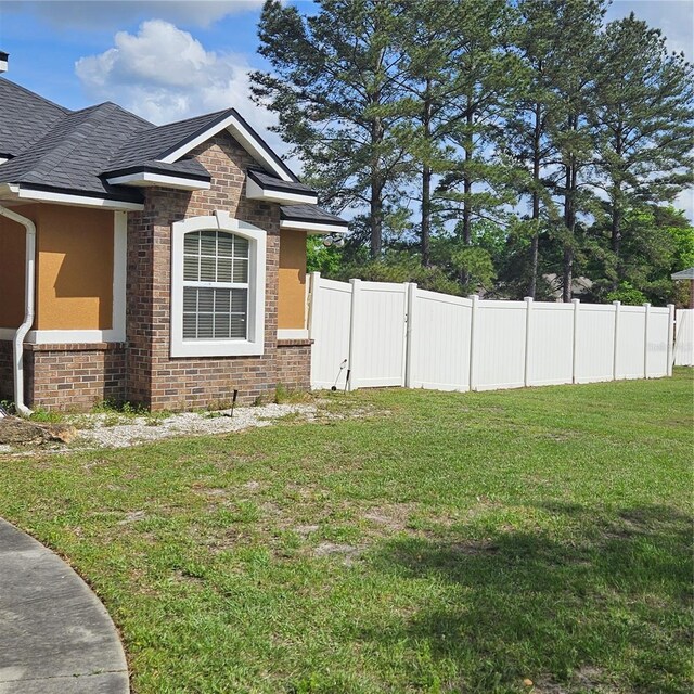 view of property exterior with stone siding, brick siding, fence, and a lawn