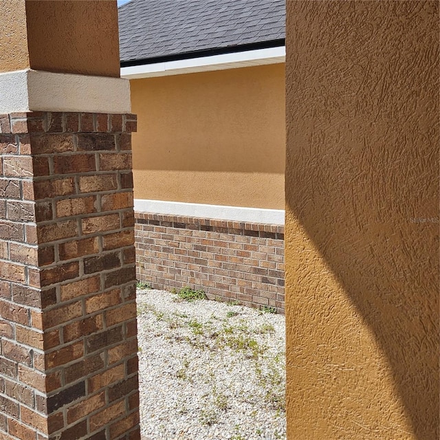 exterior details featuring a shingled roof and stucco siding