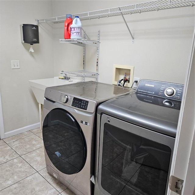 laundry room with washing machine and clothes dryer, light tile patterned flooring, baseboards, and laundry area