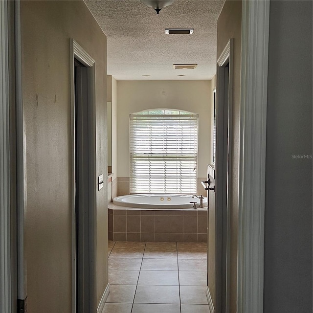 full bathroom with tile patterned floors, a garden tub, and a textured ceiling