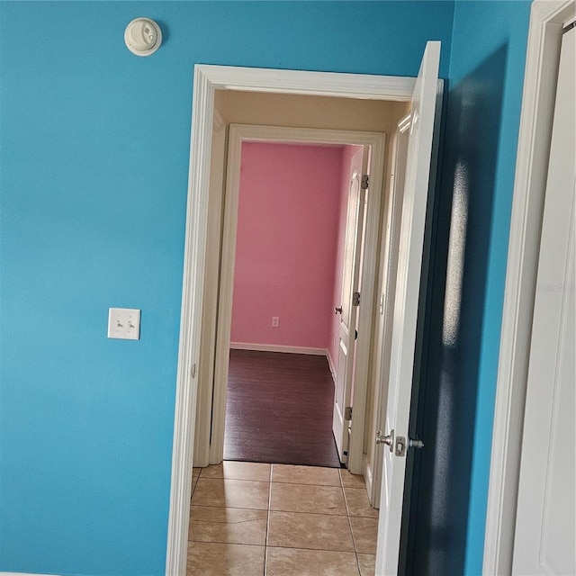 hall featuring baseboards and light tile patterned floors