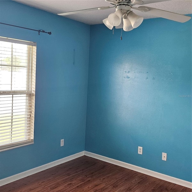 unfurnished room featuring dark wood-type flooring, baseboards, and a ceiling fan