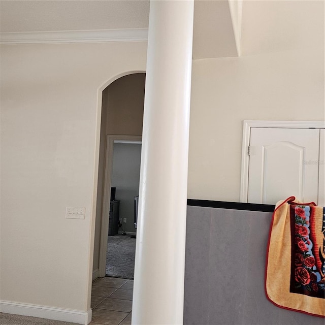 hallway with ornamental molding, tile patterned flooring, arched walkways, and baseboards