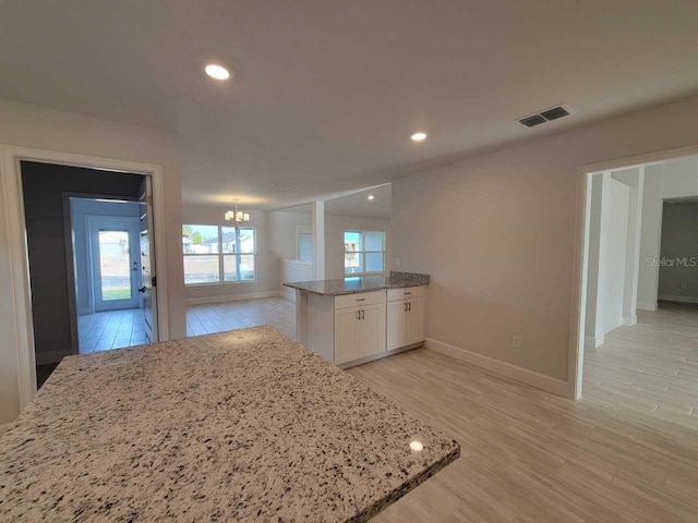 9553 SW 42nd Ave, Ocala, FL 34476 - kitchen featuring a chandelier, white cabinetry, light stone counters, baseboards, and a peninsula