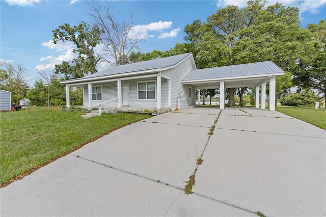 view of front of property with a porch, metal roof, a front yard, concrete driveway, and an attached carport